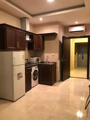 a kitchen with brown cabinets and a white refrigerator at Panda Hotel Apartments in Amman