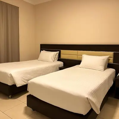 a hotel room with two beds with white sheets at Panda Hotel Apartments in Amman