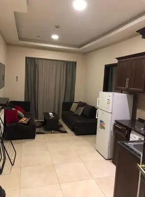 a living room with a couch and a refrigerator at Panda Hotel Apartments in Amman