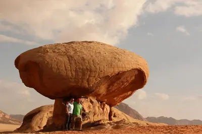 two people standing in front of a large rock at Bedouin life Camp in Wadi Rum
