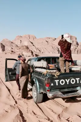 a group of people standing in the back of a truck in the desert at Bedouin life Camp in Wadi Rum