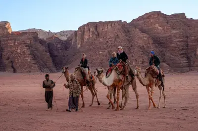 a group of people riding on camels in the desert at Desert Bird Camp in Wadi Rum