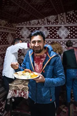 a man is holding a plate of food at Desert Bird Camp in Wadi Rum