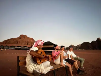 a group of people sitting on a bench in the desert at Desert Bird Camp in Wadi Rum