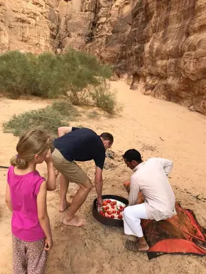a group of people standing around a tray of fruit at Wadi Rum Desert Secret in Wadi Rum