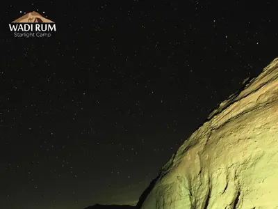 a starry night with a house on top of a mountain at Wadi Rum Starlight Camp in Wadi Rum