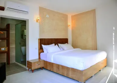 a bedroom with a large bed and a bathroom at Little Petra Bedouin Camp in Al Ḩayy