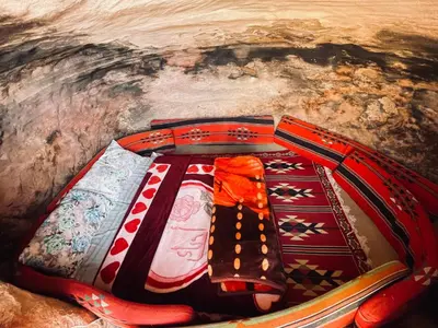 a cave with colorful blankets and pillows at Little Petra Bedouin Camp in Al Ḩayy