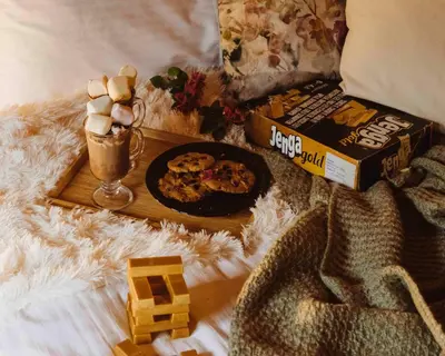 a tray of food and a drink on a bed at Mountain Breeze Lodge & Resort in Al Salt