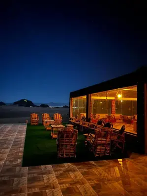 a group of chairs and tables on a patio at night at Hasan Zawaideh luxury camp 2 in Wadi Rum