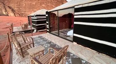 a patio with chairs and a table and a tent at Wadi Rum Sky Tours & Camp in Wadi Rum