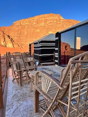 a group of chairs on a deck with a view of the desert at Wadi Rum Sky Tours & Camp in Wadi Rum
