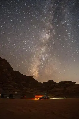 a starry night with a car parked in the desert at Wadi Rum Sky Tours & Camp in Wadi Rum