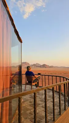 a person sitting in a chair on a deck looking at the desert at Wadi Rum Candles Camp in Wadi Rum
