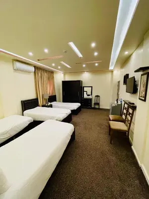 a hotel room with three beds and a tv at Esperanza Petra in Wadi Musa