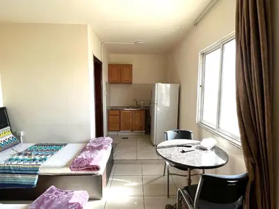 a room with a bed and a table and a kitchen at Al Qatal Building in Al Qasţal