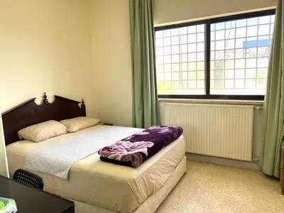 a bedroom with a bed and a large window at Al Qatal Building in Al Qasţal