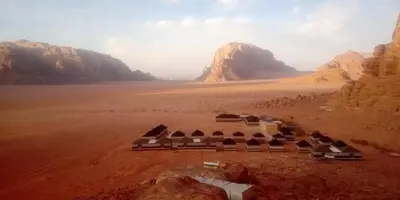 a building in the middle of a desert with mountains at Wadi Rum Quiet Village Camp in Wadi Rum