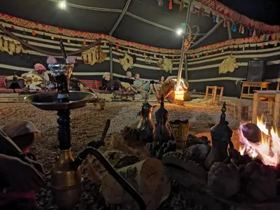a group of people sitting around a fire in a tent at Wadi Rum Dream Camp in Wadi Rum