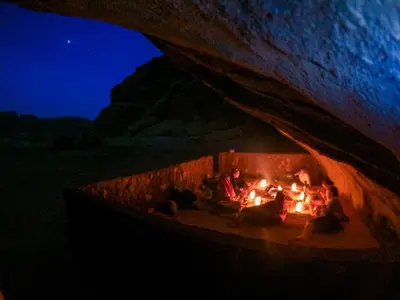 a group of people sitting around a fire in a cave at Stargazing Camp & Tours in Wadi Rum