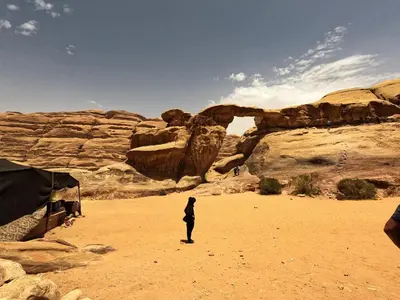a woman standing in the desert near a rock formation at Stargazing Camp & Tours in Wadi Rum