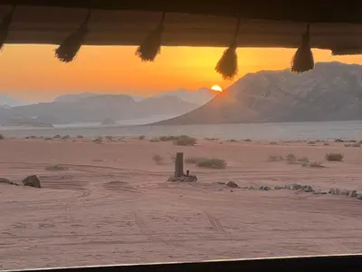 a view of the desert with the sunset in the background at Rumshines Camp in Wadi Rum