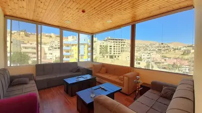 a living room with couches and tables and large windows at Petra Cabin Inn Hostel&Resturant in Wadi Musa