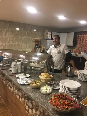 two men standing in a kitchen preparing food at Petra Cabin Inn Hostel&Resturant in Wadi Musa