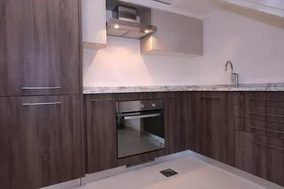a kitchen with wooden cabinets and a stove at Tala Bay Residence - Families Only in Aqaba