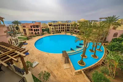 an overhead view of a large swimming pool with palm trees at Tala Bay Residence - Families Only in Aqaba