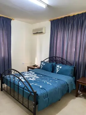 a bedroom with a bed with blue sheets and purple curtains at Sami Apartments in Amman