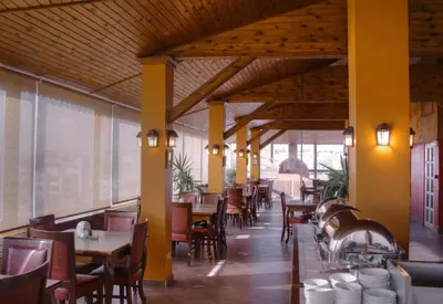 a restaurant with wooden ceilings and tables and chairs at Mariam Hotel in Madaba