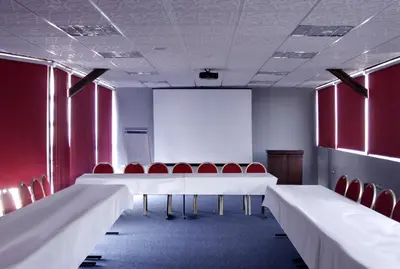 a conference room with white tables and red chairs at Mariam Hotel in Madaba