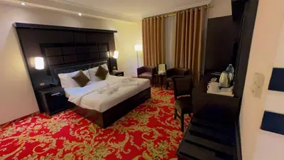 a hotel room with a large bed and a red carpet at Sparr Hotel in Amman