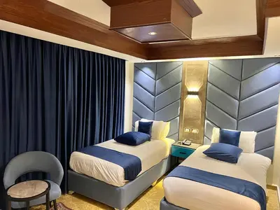 a hotel room with two beds and a chair at Petra Sella Hotel in Wadi Musa
