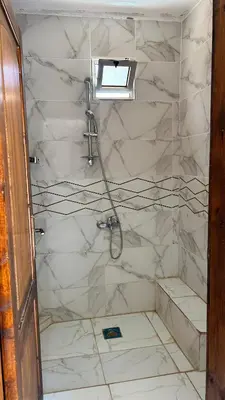 a bathroom with a shower with white marble walls at Wild of Wadi Rum in Wadi Rum