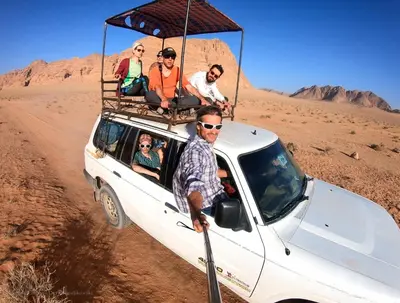 a group of people sitting in the back of a vehicle in the desert at Wild of Wadi Rum in Wadi Rum