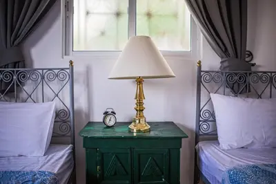 a lamp on a green table next to two beds at Beit Al Baraka in Um Qeis