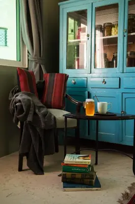 a living room with a chair and a table with books at Beit Al Baraka in Um Qeis