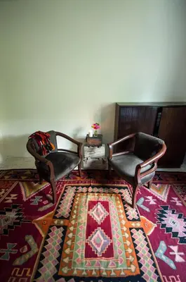 a living room with two chairs and a rug at Beit Al Baraka in Um Qeis
