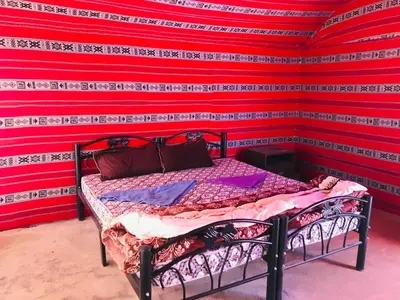 a bed in a room with a red wall at Red Mountain Camp in Wadi Rum