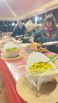 a group of people standing around a table with food at DESERT HELO lUXURY CAMP & TOUR in Wadi Rum