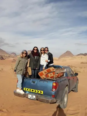 a group of people standing on the back of a car in the desert at Wadi Rum Nature Tours And Camp in Wadi Rum