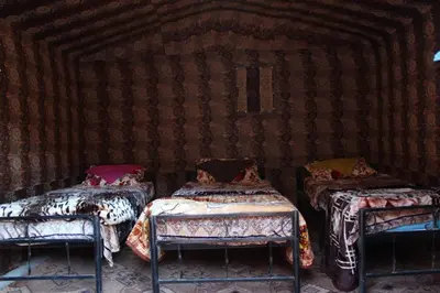 a room with three beds in a room with a wall at Wadi Rum Lawrence Camp in Wadi Rum