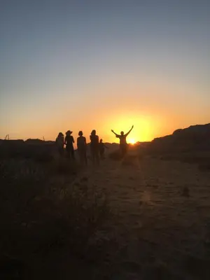 a group of people walking in the desert at sunset at Wadi Rum Lawrence Camp in Wadi Rum