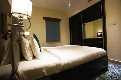 a bedroom with a white bed with a light on it at Naylover Hotel Suites in Amman