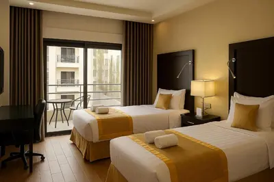 a hotel room with two beds and a balcony at Aljamal Hotel in Amman