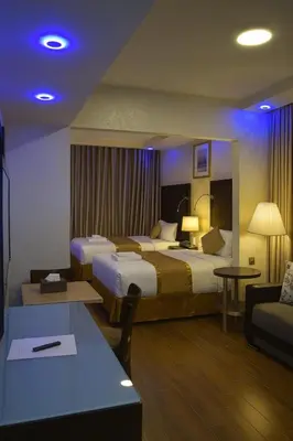 a hotel room with two beds and a couch at Aljamal Hotel in Amman