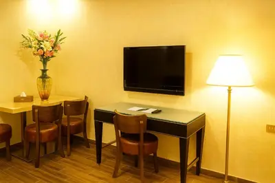 a hotel room with a desk with chairs and a tv at Aljamal Hotel in Amman