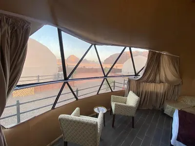 a room with two chairs and a large window at Captains Desert Camp in Wadi Rum